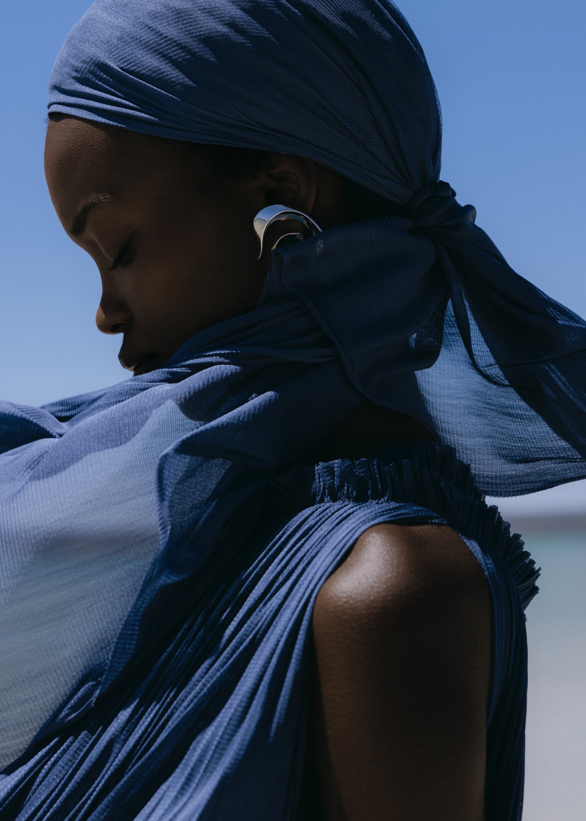 Model in a deep blue Hanne Bloch look standing on a pale beach