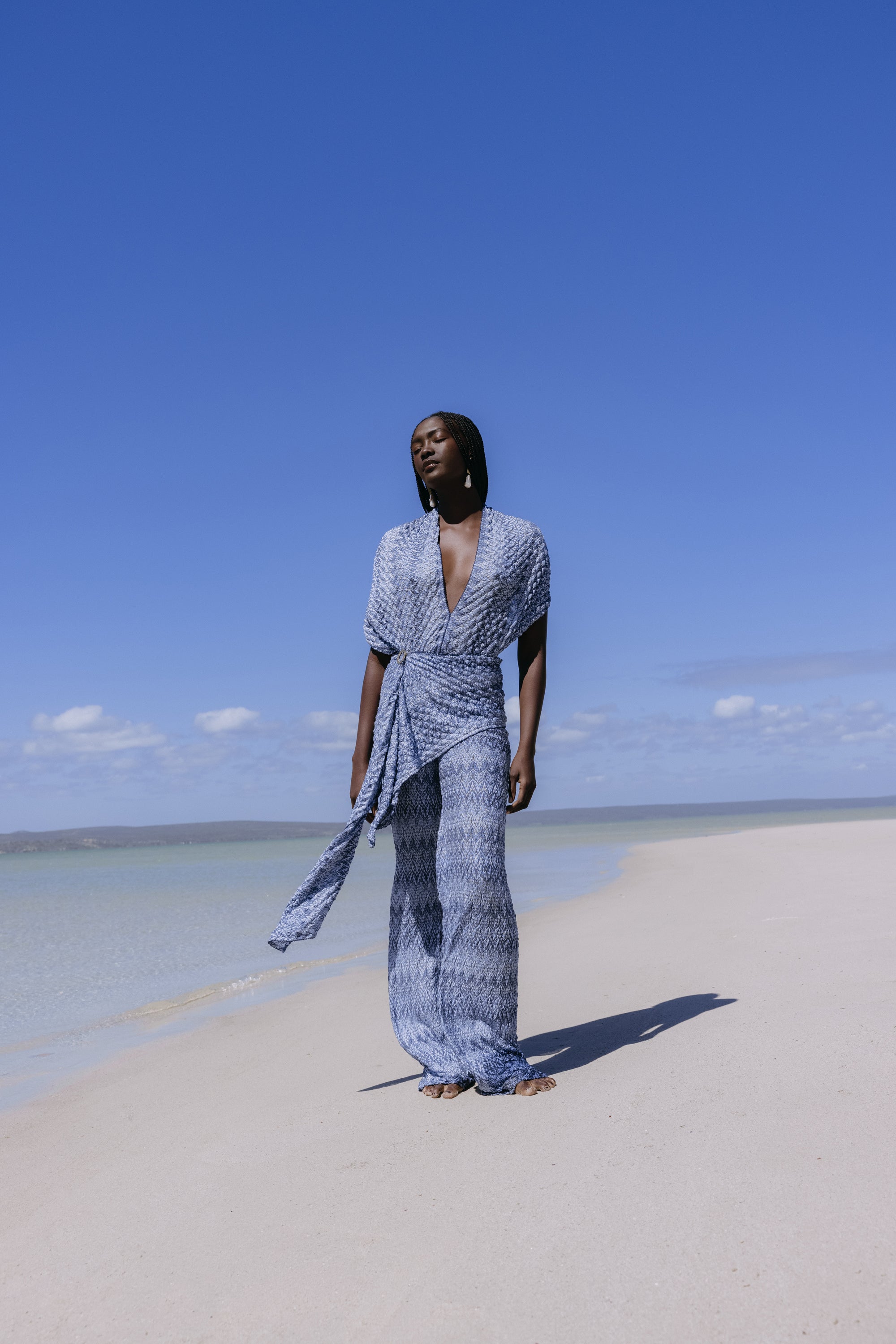 Close profile of a model wearing a deep blue Hanne Bloch scarf and pleated garment